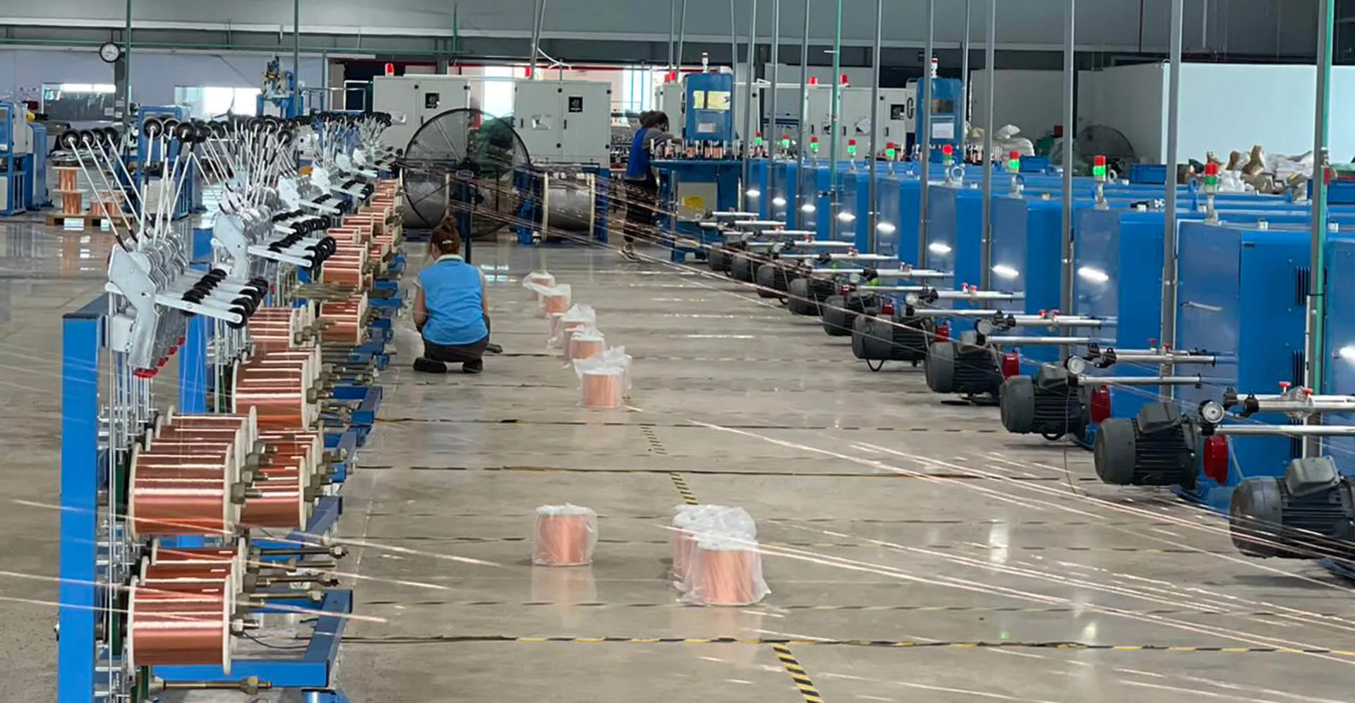 Wire-drawing and bunching hall with rows of machines and copper spools